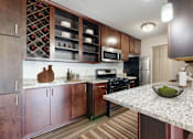 Thumbnail 7 of 20 - A kitchen with a granite countertop and wooden cabinets.
