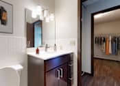 Thumbnail 16 of 20 - A bathroom with a white chair, a sink, and a mirror.