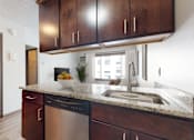 Thumbnail 15 of 20 - A kitchen with dark wood cabinets and a stainless steel dishwasher.