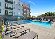 Thumbnail 79 of 91 - a swimming pool with lounge chairs and umbrellas in front of an apartment building at The Morrison, Rosemount, MN