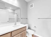 Thumbnail 46 of 97 - A white bathroom with a toilet, sink, and mirror.