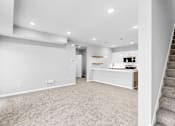 Thumbnail 17 of 97 - A spacious, empty room with a staircase on the right side.