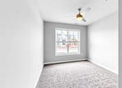 Thumbnail 6 of 97 - A room with a ceiling fan and a window overlooking a street.