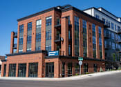 Thumbnail 32 of 45 - A red brick building with a blue sign that says "Opening Spring".