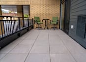 Thumbnail 20 of 45 - Two green chairs on a balcony with a brick wall.