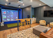 Thumbnail 4 of 45 - A modern living room with a large screen and comfortable seating.