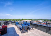 Thumbnail 24 of 45 - A rooftop patio with blue cushioned seating and a view of the city.