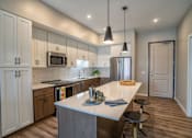 Thumbnail 39 of 45 - A kitchen with a white counter top and a large island.
