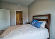 Thumbnail 40 of 45 - A bed with a white comforter and blue pillows in a room.