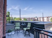 Thumbnail 19 of 45 - A balcony with a table and chairs overlooking a cityscape.