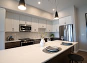 Thumbnail 34 of 45 - A modern kitchen with a white countertop and stainless steel appliances.