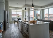 Thumbnail 11 of 45 - A modern kitchen with a large island and a view of the city.