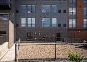 Thumbnail 58 of 69 - A grey building with a black fence and a red brick building to the right.