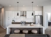 Thumbnail 12 of 69 - A modern kitchen with a bar stool and a fridge.