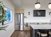 Thumbnail 49 of 69 - A kitchen with a fridge, sink, and a painting on the wall.