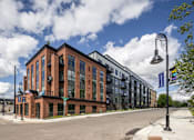 Thumbnail 1 of 69 - A street view of a building with a blue sky and clouds in the background.