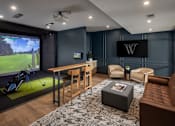 Thumbnail 40 of 69 - A modern living room with a golf simulator and a large TV.