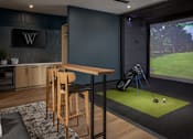 Thumbnail 41 of 69 - A room with a golf simulator and a bar area.