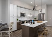 Thumbnail 4 of 69 - A kitchen with a white island and a stainless steel refrigerator.