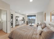 Thumbnail 1 of 105 - a bedroom with a couch and a bed and a kitchen with a window