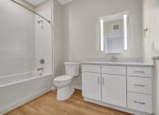 Thumbnail 83 of 105 - a bathroom with white cabinets and a white bathtub