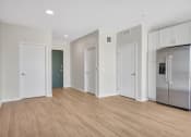 Thumbnail 79 of 105 - a bedroom with a medium sized bed and a refrigerator in a room with a hardwood floor