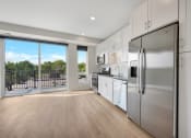 Thumbnail 72 of 105 - a kitchen with white cabinets and stainless steel appliances and a sliding glass door that leads to a