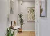 Thumbnail 9 of 105 - a hallway with white walls and a white table with a lamp on it
