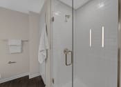 Thumbnail 45 of 105 - a white tiled bathroom with a shower and a white towel