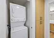 Thumbnail 2 of 60 - A white washing machine and dryer in a small laundry room.