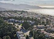 Thumbnail 28 of 47 - A coastal town with a beach and houses surrounded by trees. at Skyline Heights Apartments, Daly City, California