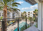 Thumbnail 22 of 60 - A balcony with a pool and palm trees.