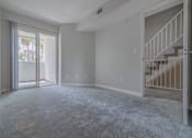 Thumbnail 15 of 23 - an empty living room with a sliding glass door and a staircase  at Warner Center Townhomes, Canoga Park, CA 91303