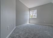 Thumbnail 17 of 23 - an empty living room with a window and carpet at Warner Center Townhomes, Canoga Park, CA