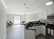 Thumbnail 1 of 23 - an empty kitchen and living room with white cabinets and black counter tops at Warner Center Townhomes, California, 91303