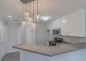 Thumbnail 4 of 23 - a kitchen with white cabinets and a counter top at Warner Center Townhomes, Canoga Park, CA 91303