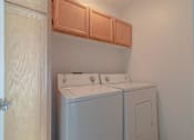 Thumbnail 12 of 23 - a washer and dryer in a room with wooden cabinets at Warner Center Townhomes, Canoga Park, CA