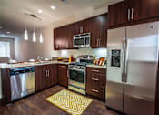 Thumbnail 4 of 45 - a kitchen with stainless steel appliances and wooden cabinets at The Vines at Riverpark, LLC, California