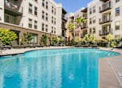 Thumbnail 4 of 60 - A swimming pool in front of apartment buildings. at Cirrus Redwood City Apartments, Redwood City, CA, 94061