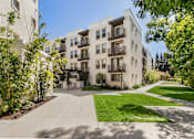 Thumbnail 18 of 60 - A sunny day at a modern apartment complex with a well-maintained lawn and trees. at Cirrus Redwood City Apartments, Redwood City