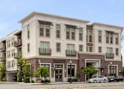 Thumbnail 21 of 60 - A modern two story building with a parking lot in front. at Cirrus Redwood City Apartments, Redwood City