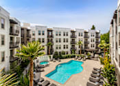 Thumbnail 6 of 60 - A swimming pool surrounded by lounge chairs and palm trees in a residential area. at Cirrus Redwood City Apartments, Redwood City, 94061