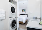Thumbnail 3 of 21 - A small white bathroom with a washing machine and a bed. at The Maddox Sunnyvale Apartments, Sunnyvale