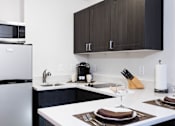 Thumbnail 4 of 21 - A modern kitchen with a white countertop and brown cabinets. at The Maddox Sunnyvale Apartments, California
