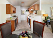 Thumbnail 7 of 21 - A kitchen with a table and chairs in the foreground. at The Maddox Sunnyvale Apartments, Sunnyvale