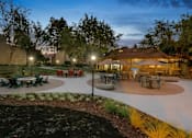 Thumbnail 25 of 90 - a patio with tables and umbrellas at night at Summerwood Apartments, Santa Clara, CA