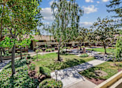 Thumbnail 1 of 90 - a courtyard with trees and grass and a building in the background at Summerwood Apartments, California