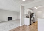 Thumbnail 74 of 90 - an empty living room with a kitchen and a fireplace at Summerwood Apartments, California