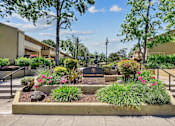 Thumbnail 47 of 90 - a community garden with flowers and trees and a sign at Summerwood Apartments, California