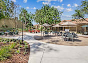 Thumbnail 58 of 90 - a patio with tables and chairs and umbrellas at Summerwood Apartments, Santa Clara